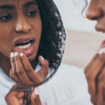 woman examines her teeth in mirror